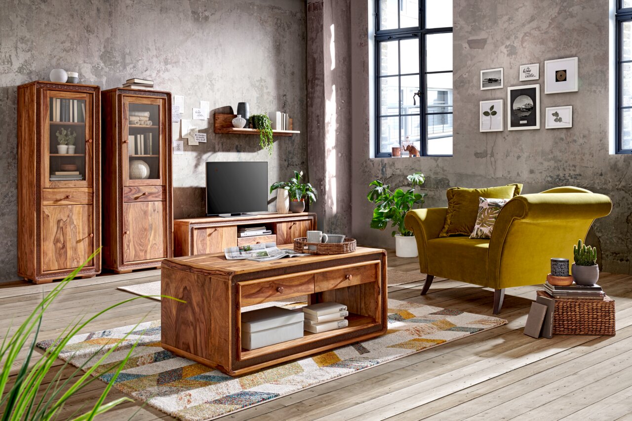 Landscape Wandboard BARCELONA Wohnzimmer mit rustikalem Couchtisch aus Holz, umgeben von grüner Samtcouch, Vitrinen und TV-Tisch, seitliche Perspektive.