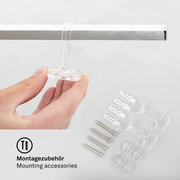 Montagezubehör für LED-Deckenleuchte, Nahaufnahme von Hand, die ein transparentes Befestigungselement hält, mit Schrauben und Dübeln im Hintergrund.