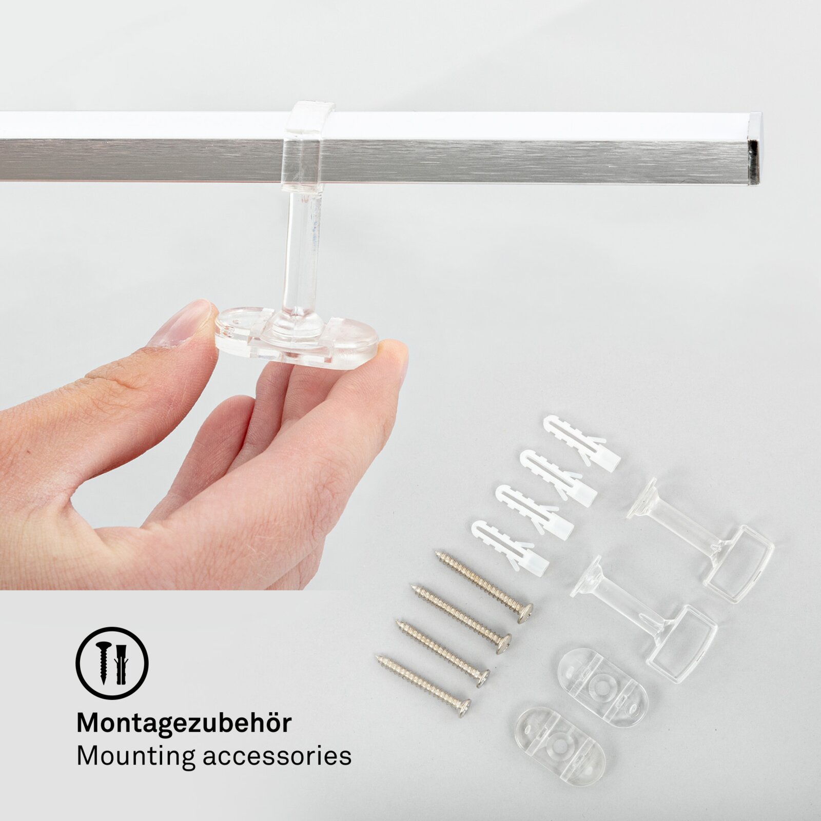Montagezubehör für LED-Deckenleuchte, Nahaufnahme von Hand, die ein transparentes Befestigungselement hält, mit Schrauben und Dübeln im Hintergrund.