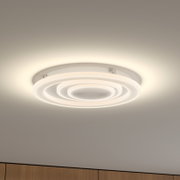 Weiße, runde LED-Deckenleuchte mit konzentrischen Leuchtringen an der Zimmerdecke, warmweiß leuchtend, Perspektive von unten schräg nach oben