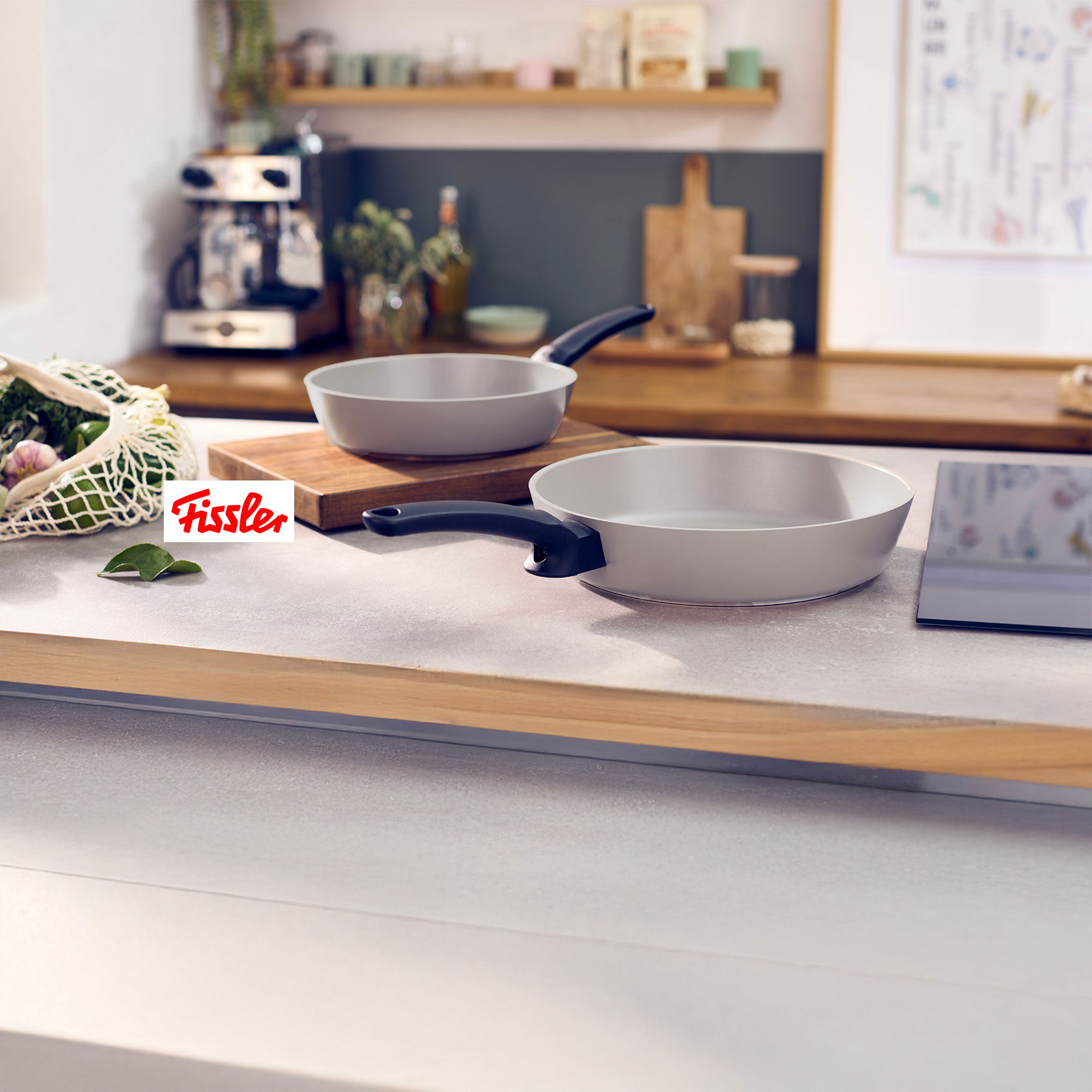 Zwei helle Fissler-Bratpfannen mit schwarzen Griffen auf moderner Küchenarbeitsplatte