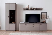 Modernes Wohnzimmer-Entertainment-Set in Taupe mit TV-Lowboard, hohem Schrank mit Glasvitrine und schwebendem Wandregal, frontal aus Augenhöhe fotografiert.