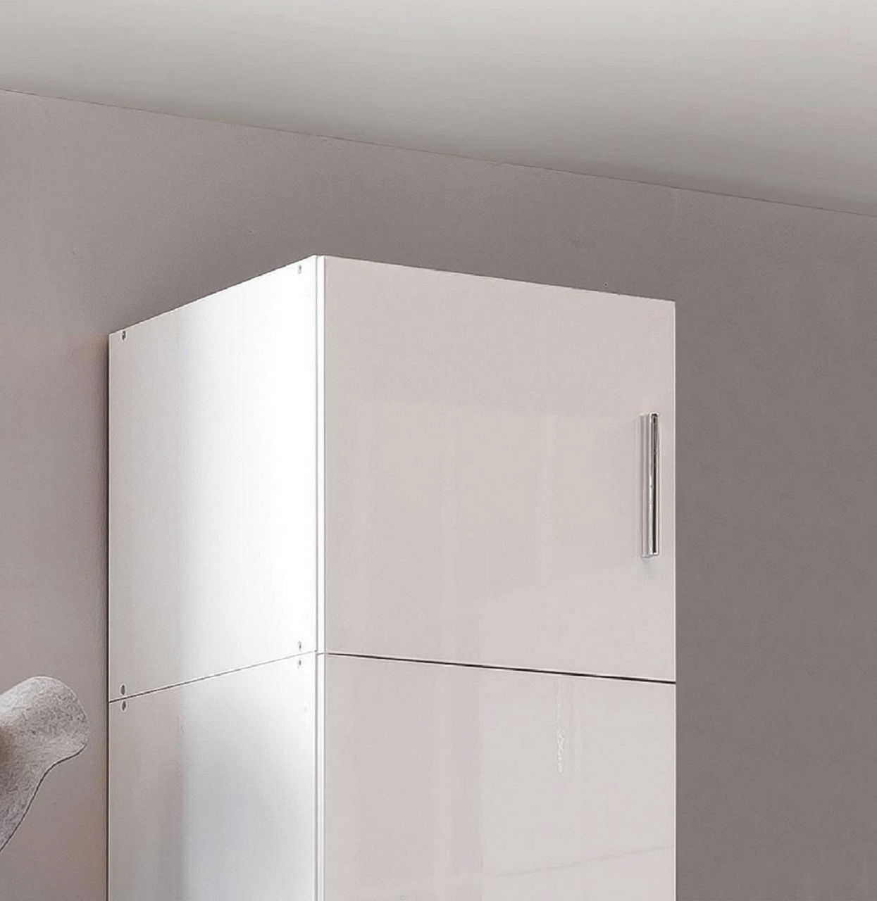 Weißer Schrankaufsatz mit glänzender Oberfläche und silbernem Griff, seitliche Perspektive