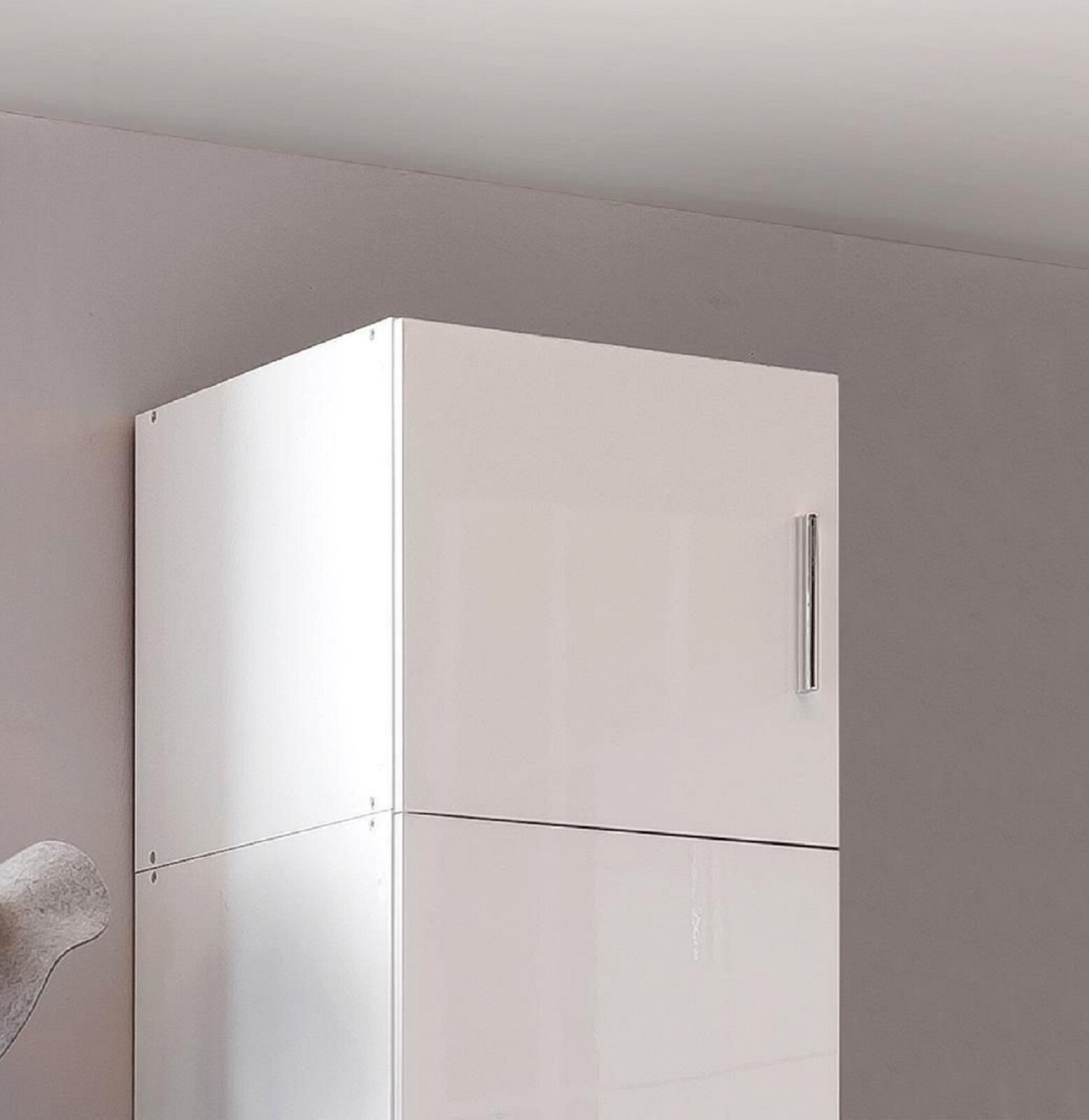 Weißer Schrankaufsatz mit glänzender Oberfläche und silbernem Griff, seitliche Perspektive