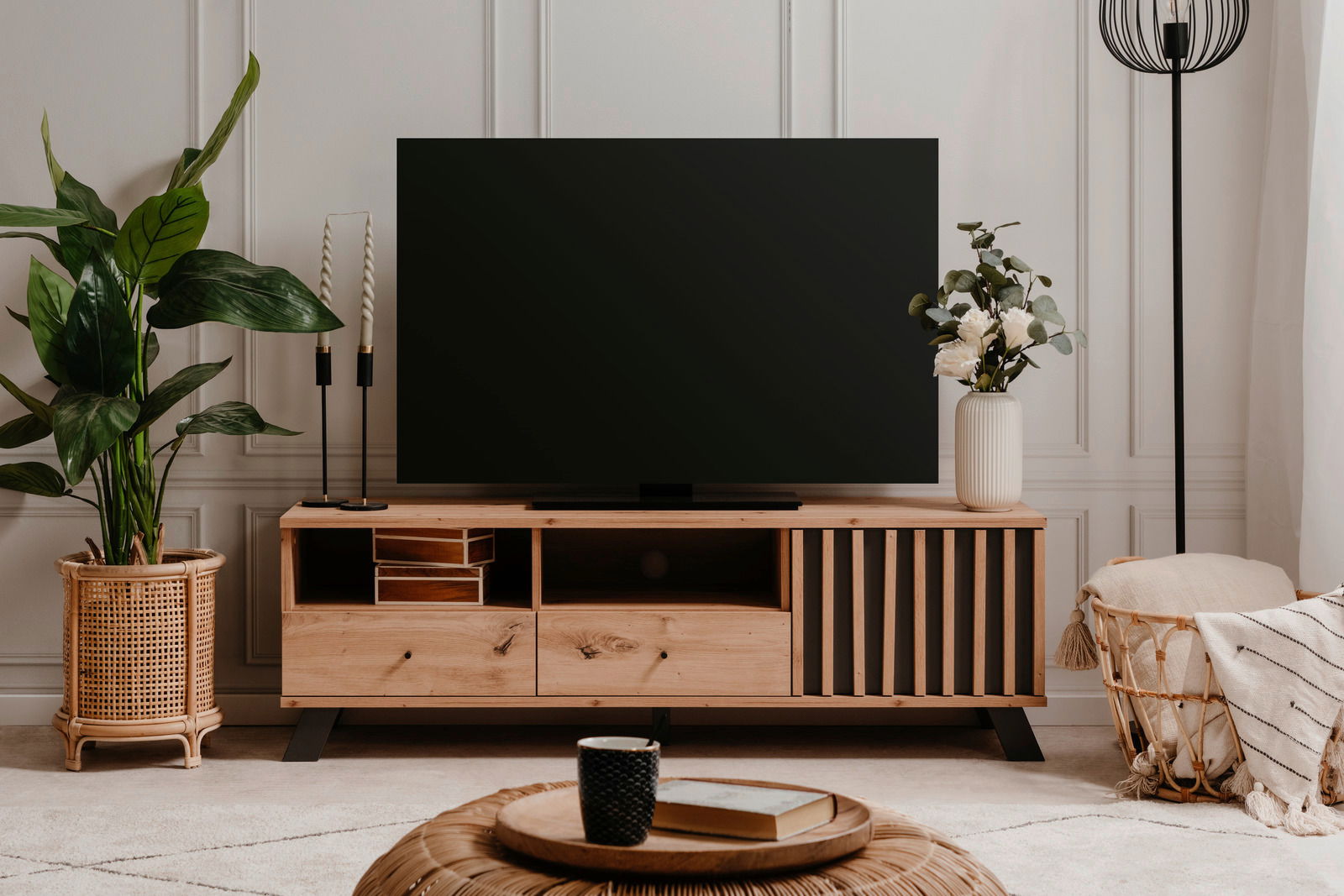 Z2 TV-Lowboard MEDAN Frontale Ansicht eines stilvollen TV-Lowboards aus Holz mit dekorativen Elementen, einem großen Fernseher darauf und Pflanzen sowie Dekorationen daneben.