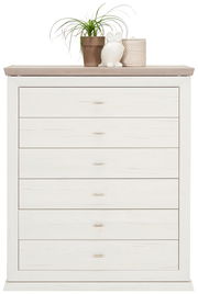 Weiße Kommode mit sechs Schubladen, dekoriert mit einer Pflanze, einer Eulenfigur und einem Korb auf der Oberseite, Frontalansicht.