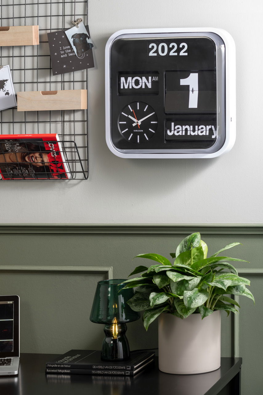 KARLSSON Big Flip Wanduhr Moderne Wanduhr mit Kalenderfunktion, zeigt Montag, 1. Januar 2022 an, in einem stilvollen Raum mit Pflanzen und Dekoration, Frontalansicht.