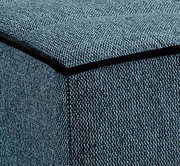 Nahaufnahme eines blauen Stoffbezugs mit schwarzer Kante, perspektivisch von der Ecke eines Schlafsofas.