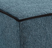 Nahaufnahme eines blauen Stoffbezugs mit schwarzer Kante, perspektivisch von der Ecke eines Schlafsofas.