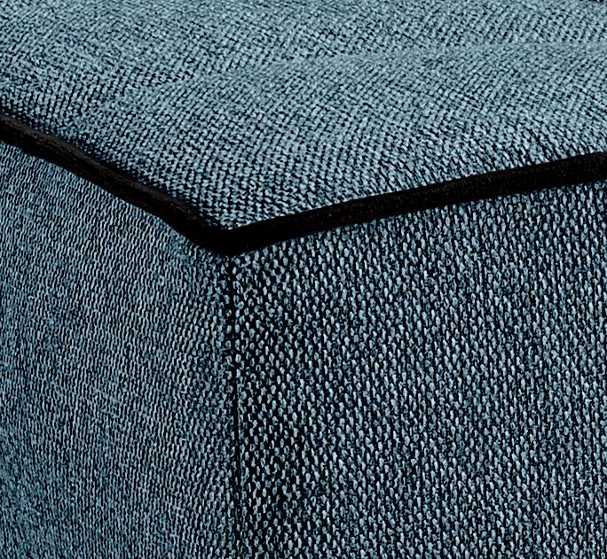 Nahaufnahme eines blauen Stoffbezugs mit schwarzer Kante, perspektivisch von der Ecke eines Schlafsofas.