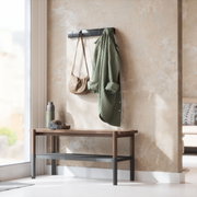 Moderne Wandgarderobe Umbra FLIP in einem hellen Raum, frontal an der Wand montiert, mit einem grünen Hemd und einer Tasche behängt.