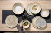 Verschillende borden en schalen met decoratieve patronen, van bovenaf gefotografeerd op een houten tafel met een donker tafelkleed.
