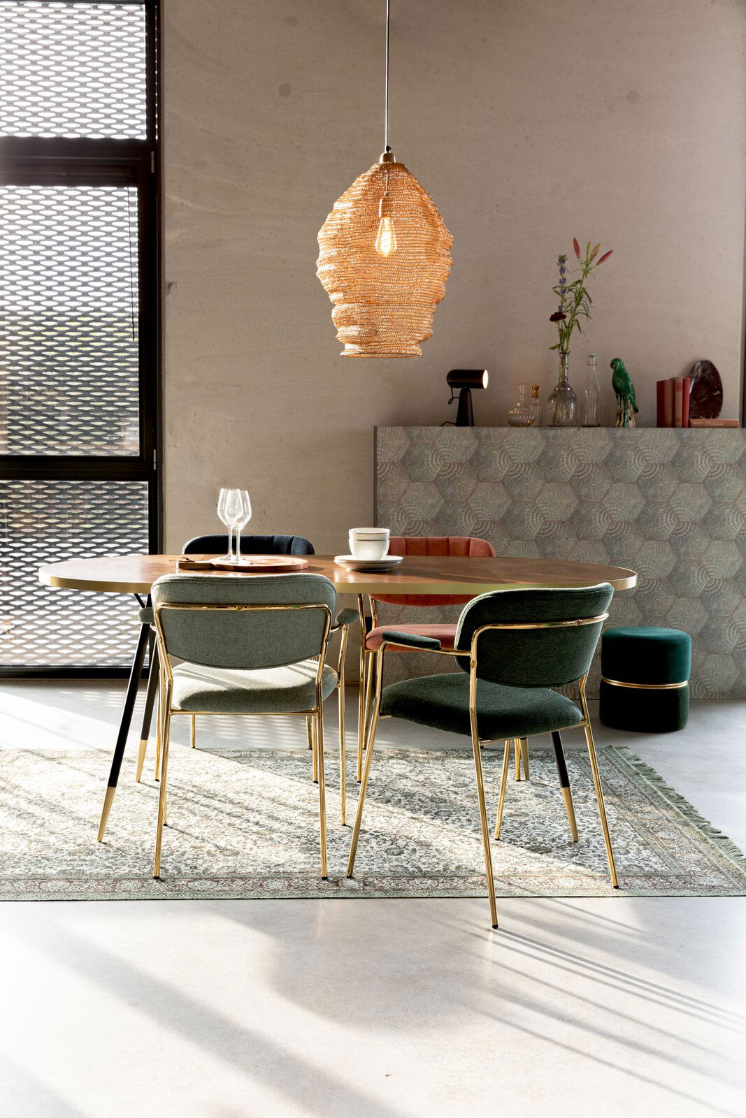 Z2 Armlehnenstuhl JOLIEN Esszimmer mit einem runden Tisch und mehreren Armlehnenstühlen in verschiedenen Farben, von hinten betrachtet. Im Hintergrund eine moderne Hängelampe und Dekorationen.