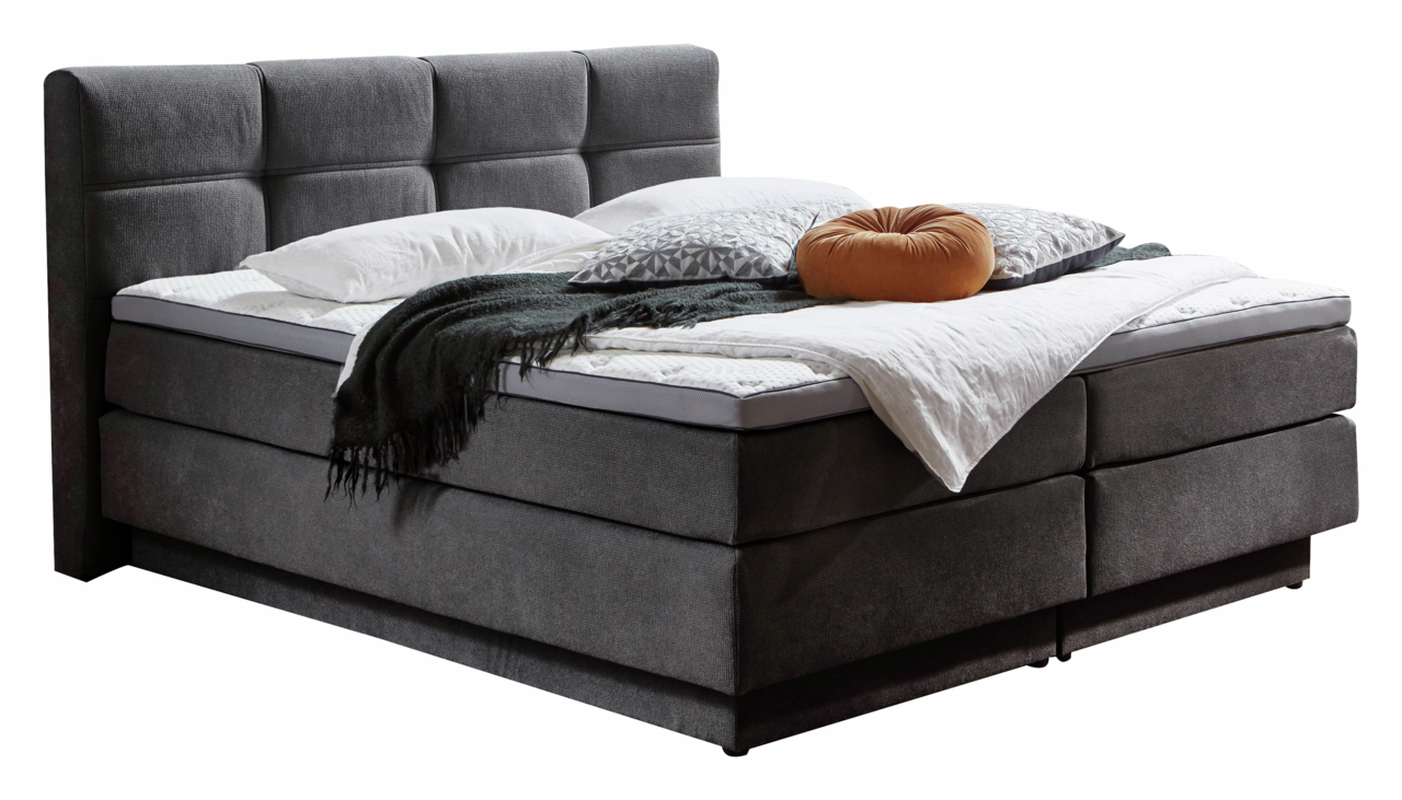 Boxspringbett in dunklem Stoffbezug mit hohem, gepolstertem Kopfteil, seitliche Perspektive