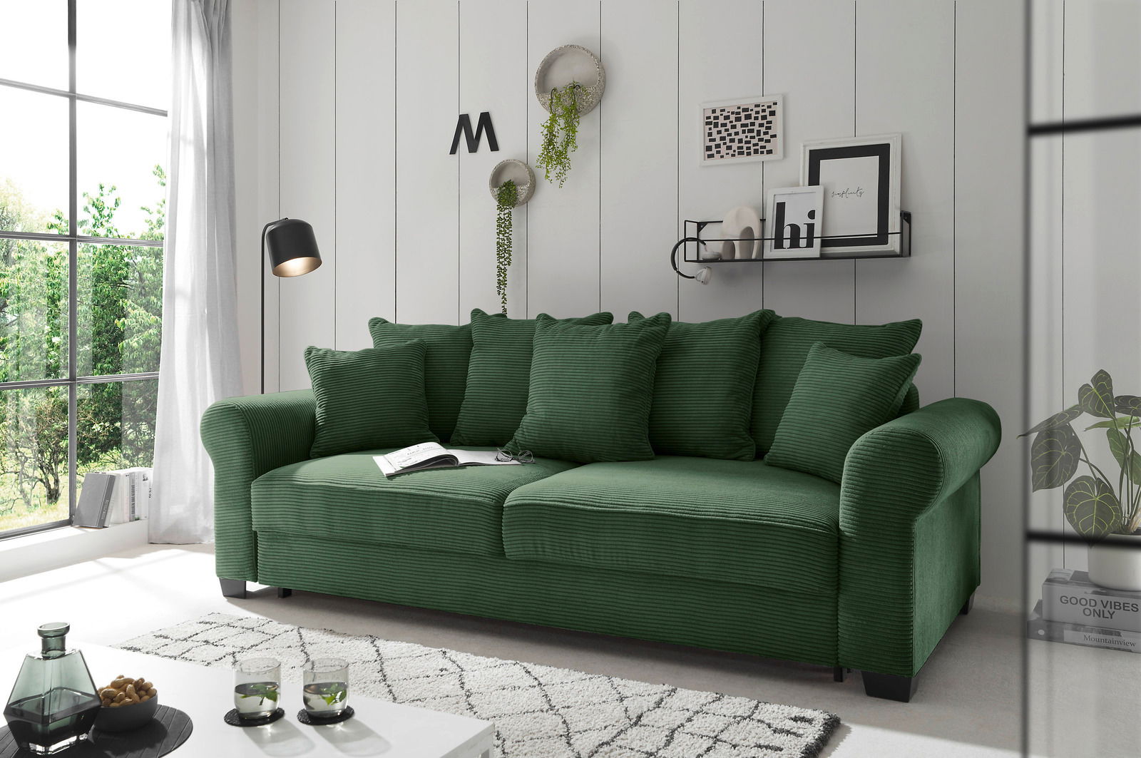 Hom´in Big Sofa MAUREEN Grünes Funktionssofa mit mehreren Kissen, seitliche Perspektive, in einem modernen Wohnzimmer mit großen Fenstern und stilvoller Dekoration.