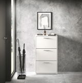 Moderner weißer Schuhkipper mit drei Klappen, frontal fotografiert, neben einem Regenschirmständer in einem stilvollen Eingangsbereich.