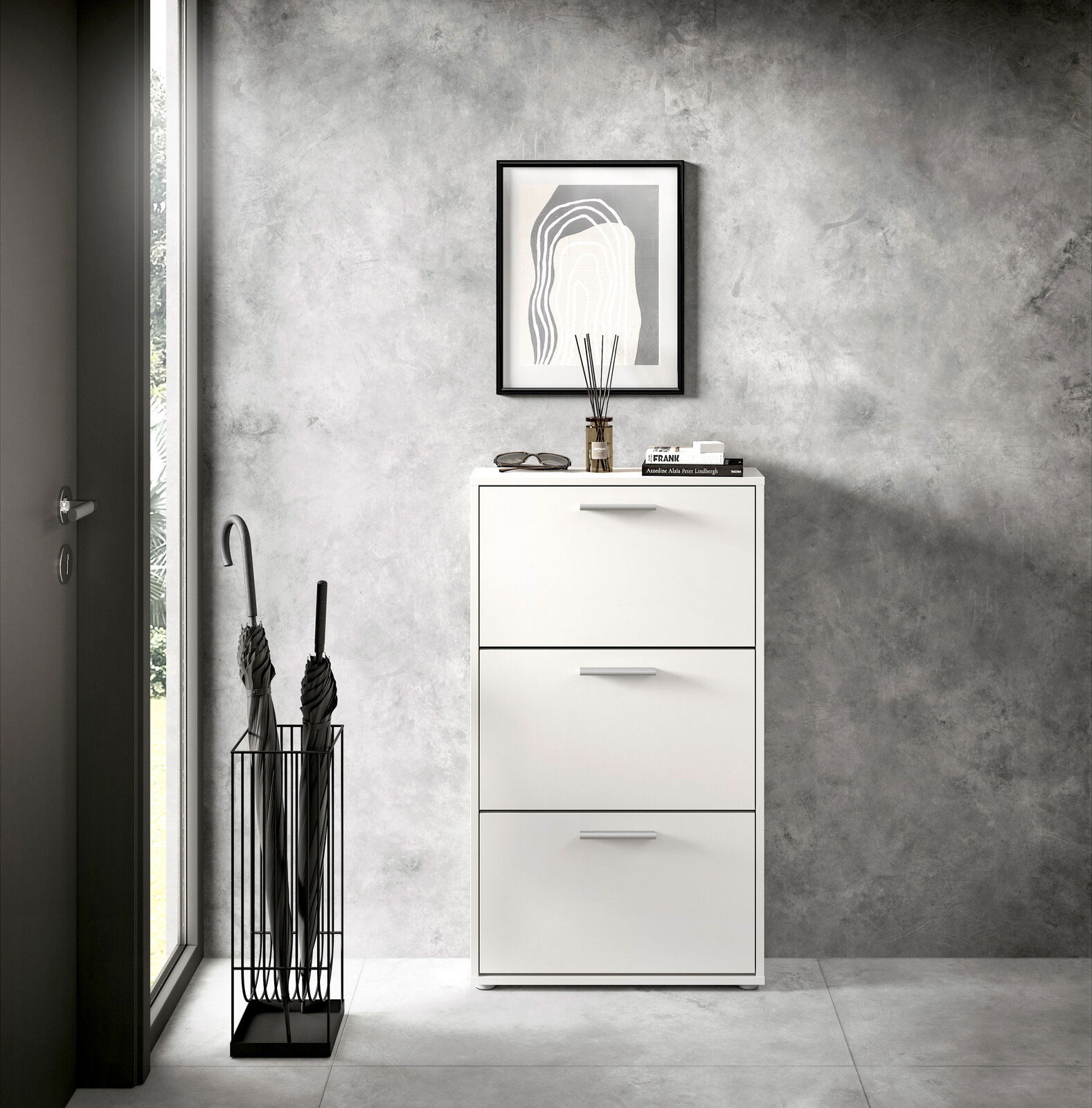 Moderner weißer Schuhkipper mit drei Klappen, frontal fotografiert, neben einem Regenschirmständer in einem stilvollen Eingangsbereich.