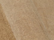 Nahaufnahme eines beigen Wollteppichs mit weicher Textur, schräg von der Seite fotografiert.