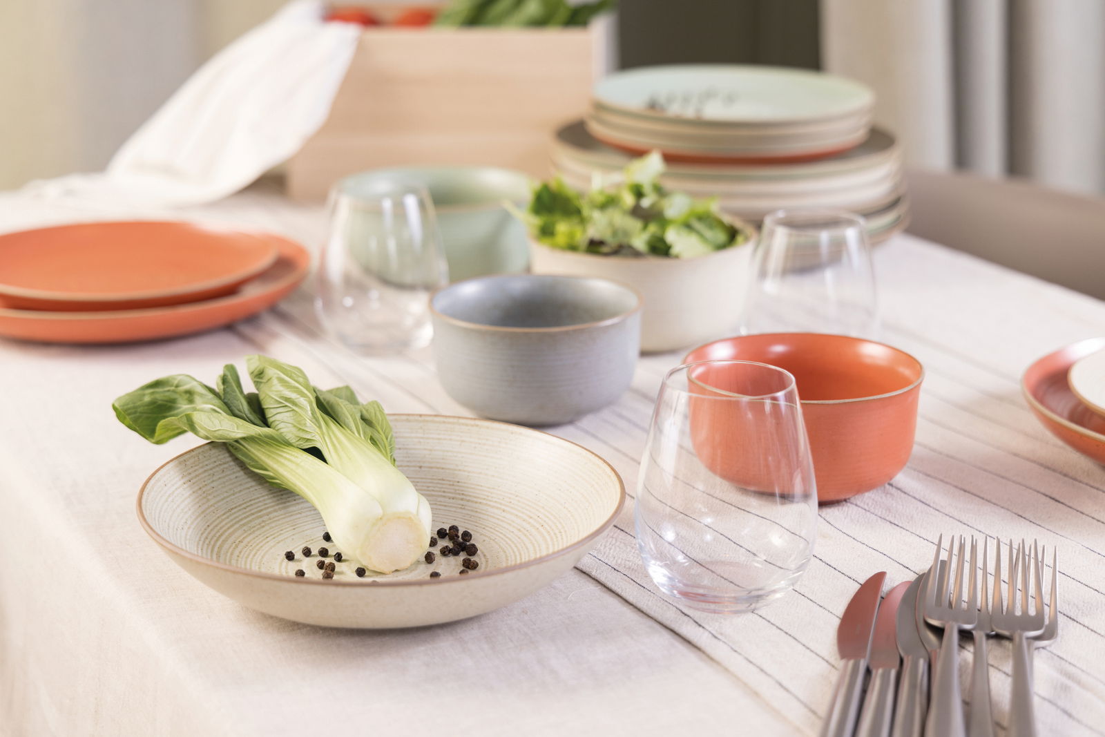 Thomas Suppenteller NATURE Suppenteller 23 cm auf einem gedeckten Tisch, gefüllt mit Pak Choi und Pfefferkörnern, aus einer seitlichen Perspektive fotografiert.