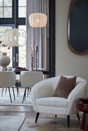 Braunes Kissen LINA 45x45 cm auf einem cremefarbenen Sessel in einem stilvoll eingerichteten Wohnzimmer, seitliche Perspektive.