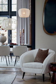 Braunes Kissen LINA 45x45 cm auf einem cremefarbenen Sessel in einem stilvoll eingerichteten Wohnzimmer, seitliche Perspektive.