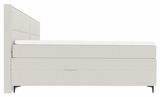 Seitliche Ansicht eines modernen Boxspringbetts mit hellem Stoffbezug und schwarzem Fußdesign.