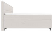 Seitliche Ansicht eines modernen Boxspringbetts mit hellem Stoffbezug und schwarzem Fußdesign.