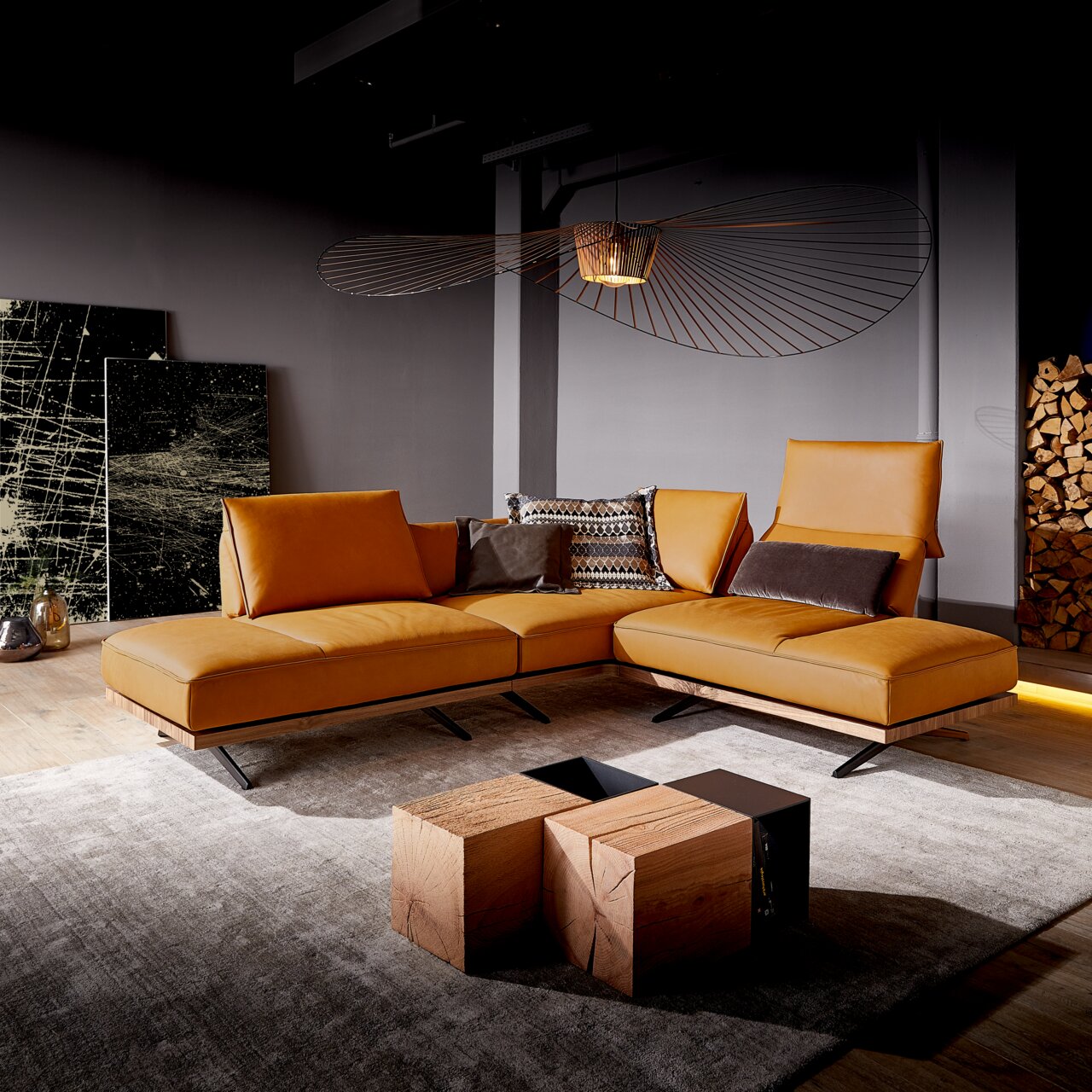 Moderne Eckgarnitur in warmem Cognac-Leder, seitliche Perspektive, mit stilvollen Kissen und dekorativen Elementen in einem eleganten Wohnzimmer.
