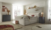 Modernes Boxspringbett in einem hellen Schlafzimmer mit großen Fenstern, seitliche Perspektive