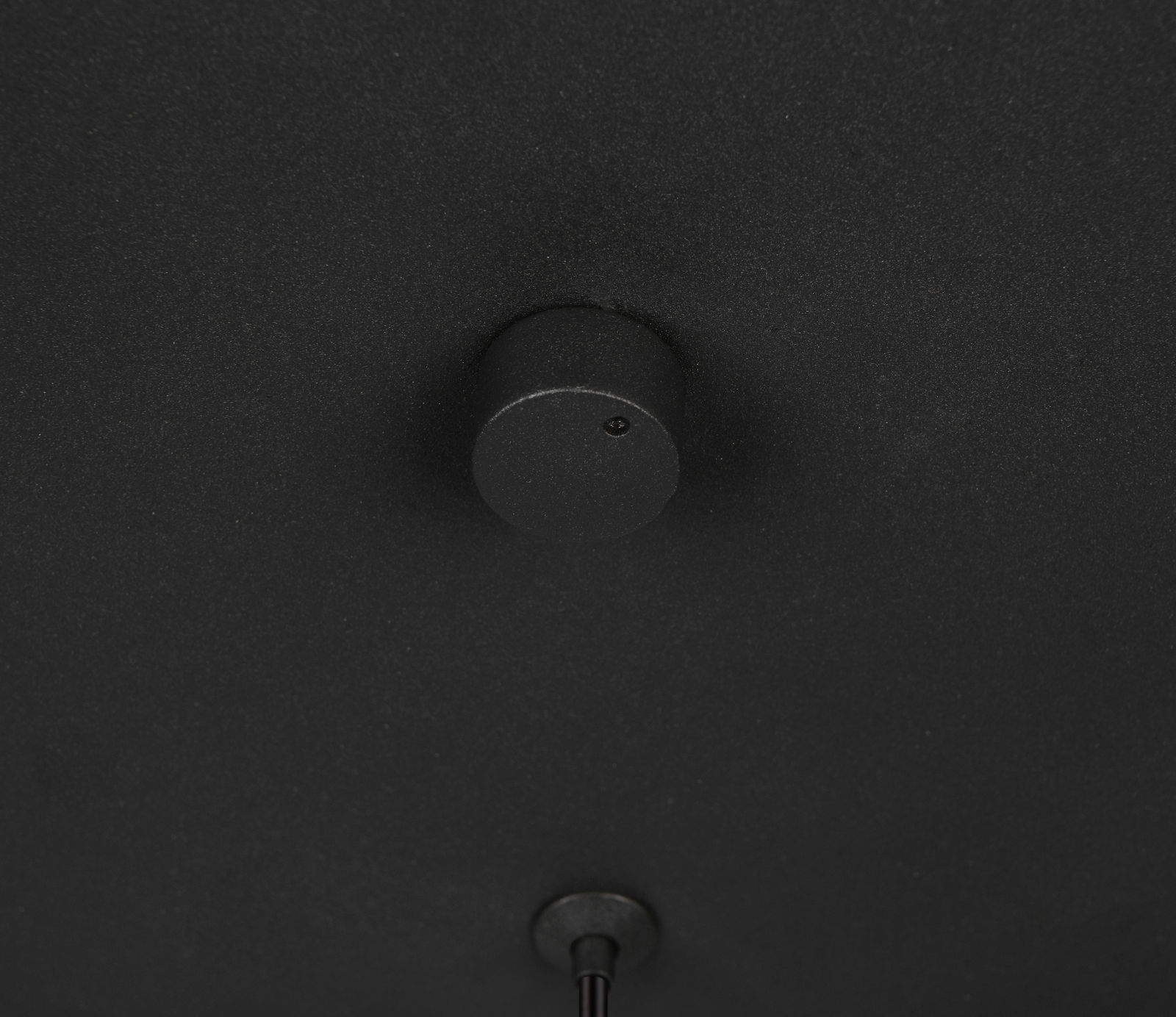 Nahaufnahme der schwarzen Deckenhalterung einer Pendelleuchte von unten betrachtet.