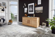 Holz-Sideboard in einem modernen Wohnzimmer, frontal fotografiert, mit Dekorationen und Wandbildern im Hintergrund.