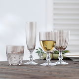 Vier rauchbraune Gläser in verschiedenen Formen und Größen auf einem Holztisch, seitliche Perspektive.