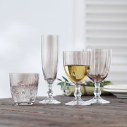 Vier rauchbraune Gläser in verschiedenen Formen und Größen auf einem Holztisch, seitliche Perspektive.