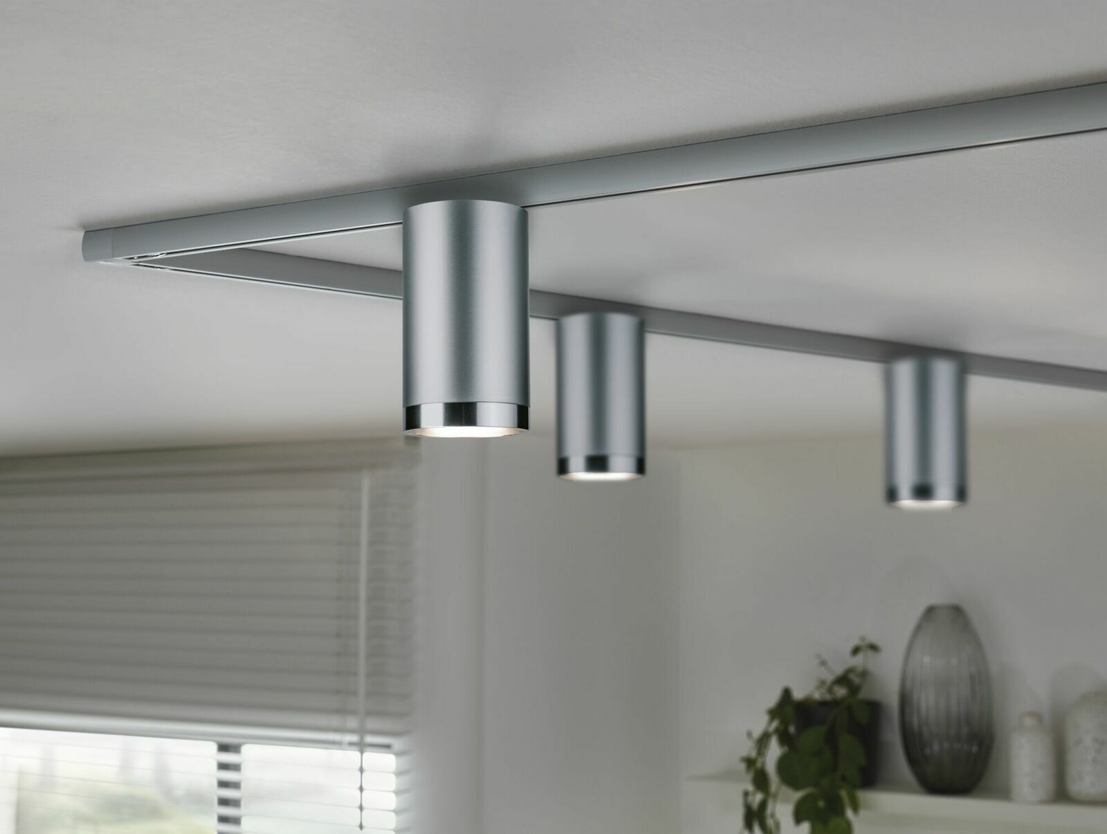 Silberner Schienenspot Tube an der Decke montiert, seitliche Perspektive, mit mehreren Spots in einem modernen Wohnraum.