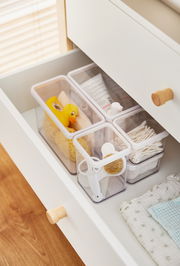 Blick von oben auf ein Utensilo-Set in einer Schublade, gefüllt mit verschiedenen Haushaltsgegenständen wie einer gelben Gummiente, Wattestäbchen und einer Bürste.