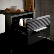 Schwarzer Standschrank LINUS mit geöffneter Schublade, seitliche Perspektive, zeigt Innenraum mit gelagerten Gegenständen.