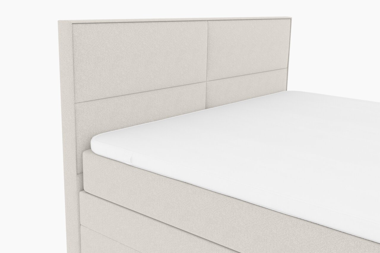 Boxspringbett in seitlicher Perspektive mit hellem Stoffbezug und gepolstertem Kopfteil