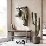 Wandgarderobe mit Rucksack und Jacke, daneben eine Bank mit Kopfhörern und Trinkflasche, im Vordergrund ein Kaktus. Perspektive: seitlich.