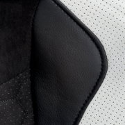 Close-up van de bekleding van een gamingstoel met zwart en wit kunstleer, gezien vanaf de zijkant