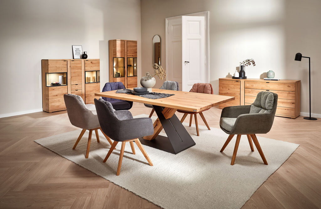 Moderner Esstisch aus Holz mit schwarzem Metallgestell, umgeben von gepolsterten Stühlen in einem stilvoll eingerichteten Esszimmer, seitliche Perspektive.