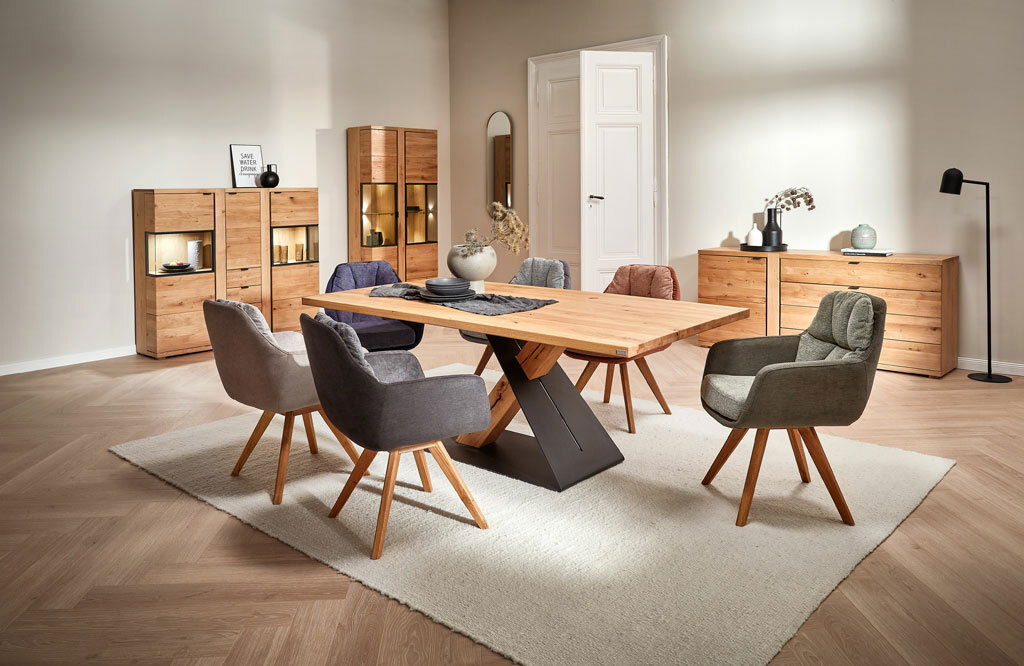 Moderner Esstisch aus Holz mit schwarzem Metallgestell, umgeben von gepolsterten Stühlen in einem stilvoll eingerichteten Esszimmer, seitliche Perspektive.