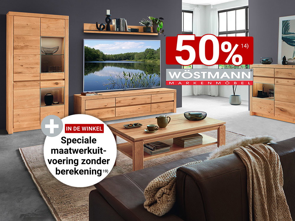 Modern ingerichte woonkamer met massieve eikenhouten meubels van Wöstmann, bestaande uit een vitrinekast, tv-lowboard, dressoir en salontafel tegen een donkergrijze wandafwerking.