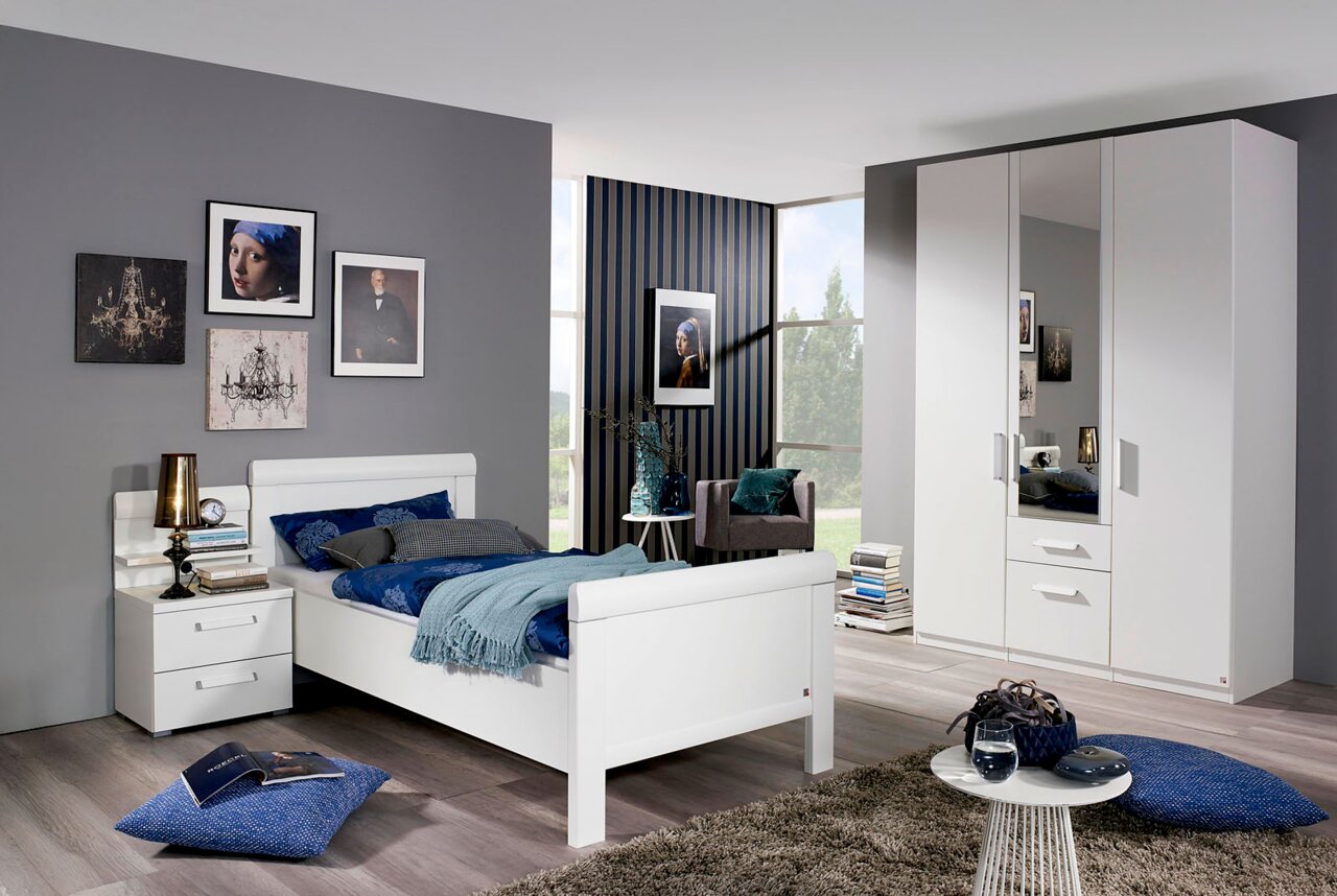 Modernes Schlafzimmer mit weißem Komfortbett, Nachttisch und dreitürigem Drehtürenschrank, seitliche Perspektive.