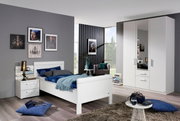 Modernes Schlafzimmer mit weißem Komfortbett, Nachttisch und dreitürigem Drehtürenschrank, seitliche Perspektive.