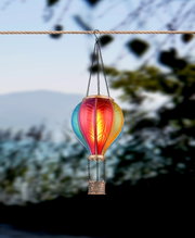 Bunte Solarleuchte in Form eines Heißluftballons, aufgehängt an einem Seil, seitliche Perspektive