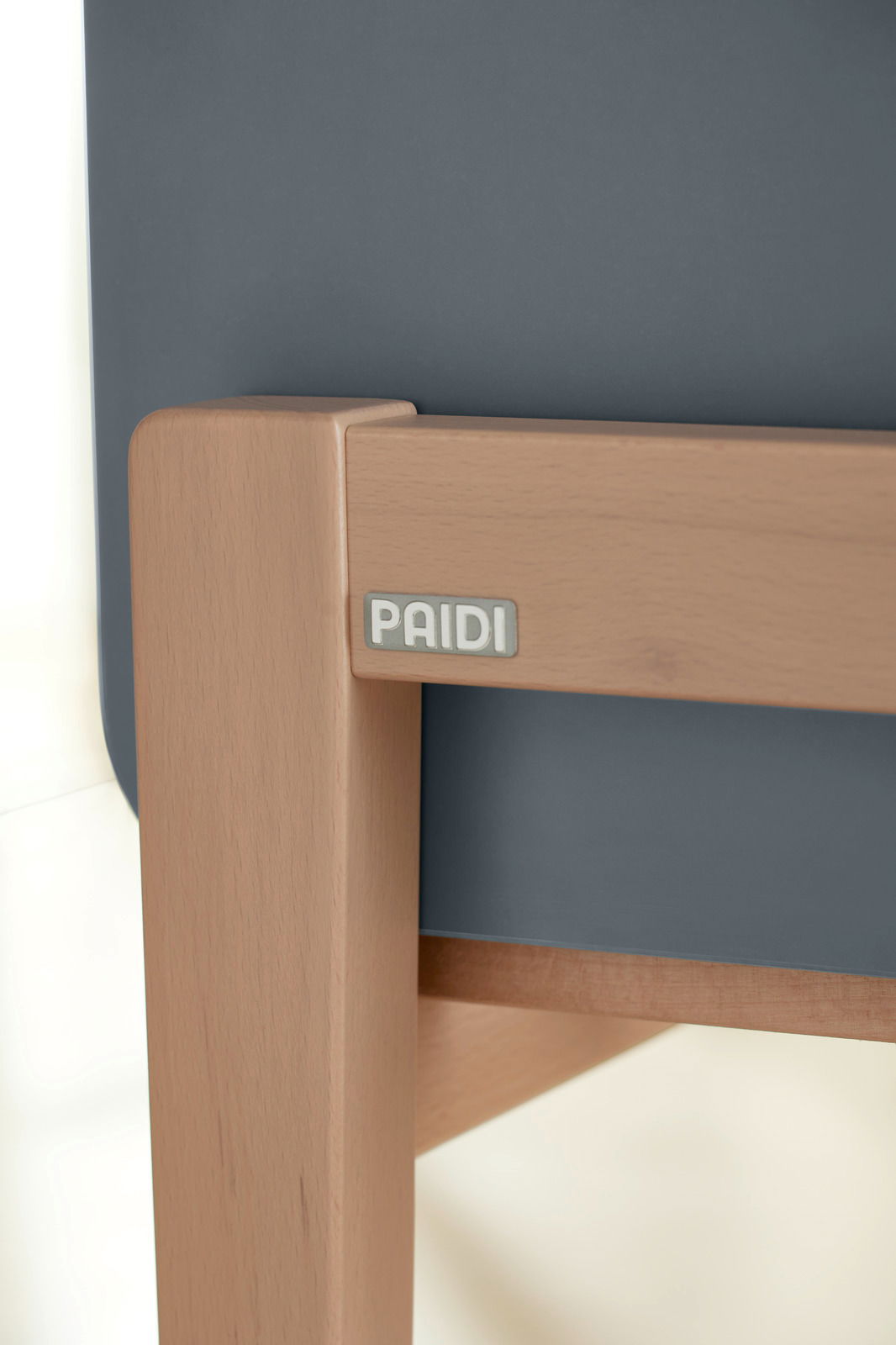 Nahaufnahme eines Anstellbetts mit Holzrahmen und dunkelgrauer Polsterung, seitliche Perspektive.