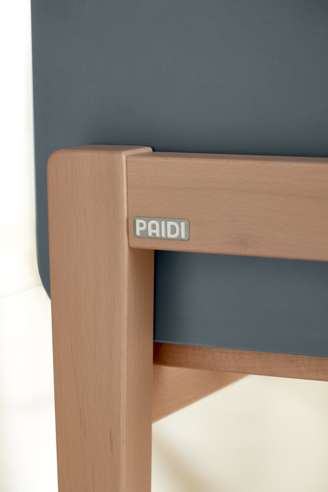 Close-up van een opklapbed met houten frame en donkergrijze bekleding, gezien vanaf de zijkant.