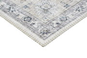 Ecke eines klassischen Teppichs mit floralen Mustern in sanften Beige- und Blautönen, aus einer schrägen Perspektive fotografiert.