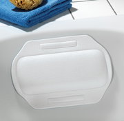 Weißes Nackenpolster in einer Badewanne, von oben fotografiert, mit blauer Handtuchrolle und Schwamm im Hintergrund.