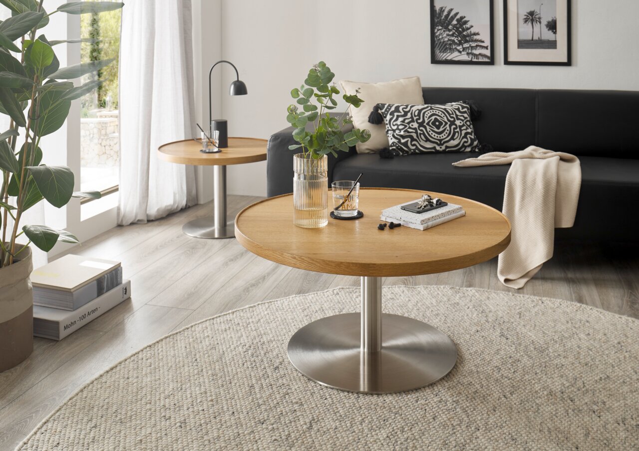 Moderne salontafel met rond houten blad en metalen onderstel, in de woonkamer met bank en decoraties, zijaanzicht